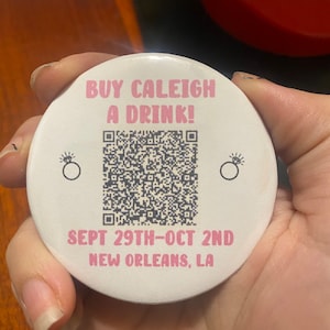 May include: White round button with pink text that reads "Buy Caleigh a Drink!" and a QR code. The text "Sept 29th-Oct 2nd New Orleans, LA" is also on the button.
