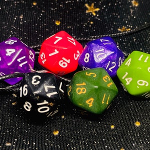 May include: A collection of six multi-sided dice in various colors, including purple, red, blue, green, black, and green. Each die features white or gold numbering. The dice are arranged on a black surface.