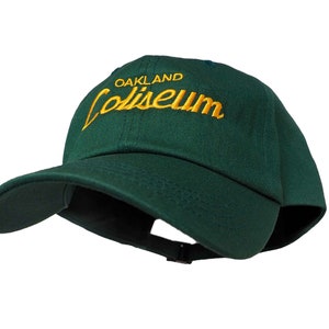 May include: A dark green baseball cap with a yellow embroidered logo that reads "Oakland Coliseum."