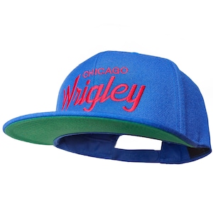 Op de afbeelding: Een blauwe en groene baseballpet met de tekst "CHICAGO WRIGLEY" in rood geborduurd op de voorkant.