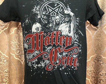 Può includere: Maglietta nera con una stampa grafica di una band chiamata "Wiffle Cruif". La grafica presenta quattro persone davanti a un pentagramma con una stella al centro. Il nome della band è in rosso e bianco.