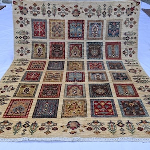 Könnte beinhalten: Ein großer, rechteckiger beigefarbener Teppich mit einem sich wiederholenden Muster aus quadratischen Designs in verschiedenen Farben. Jedes Quadrat weist aufwendige Blumen- und geometrische Motive in Rot-, Blau- und Brauntönen auf. Der Teppich hat einen dekorativen Rand mit floralen Elementen.