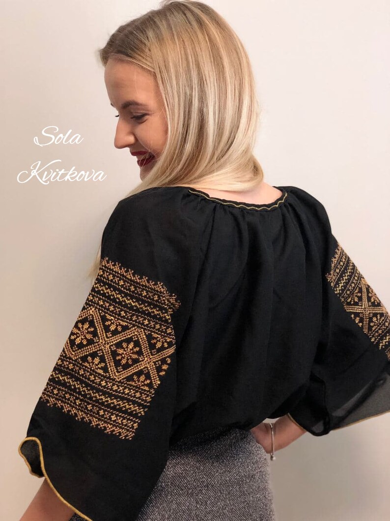 Pu&ograve; includere: Una blusa nera con ricami dorati sulle maniche. I ricami presentano motivi geometrici. La blusa ha un collo rotondo e una vestibilit&agrave; ampia.