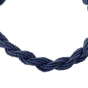 May include: A navy blue beaded necklace with a twisted design.