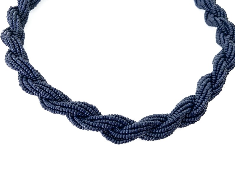 May include: A navy blue beaded necklace with a twisted design.