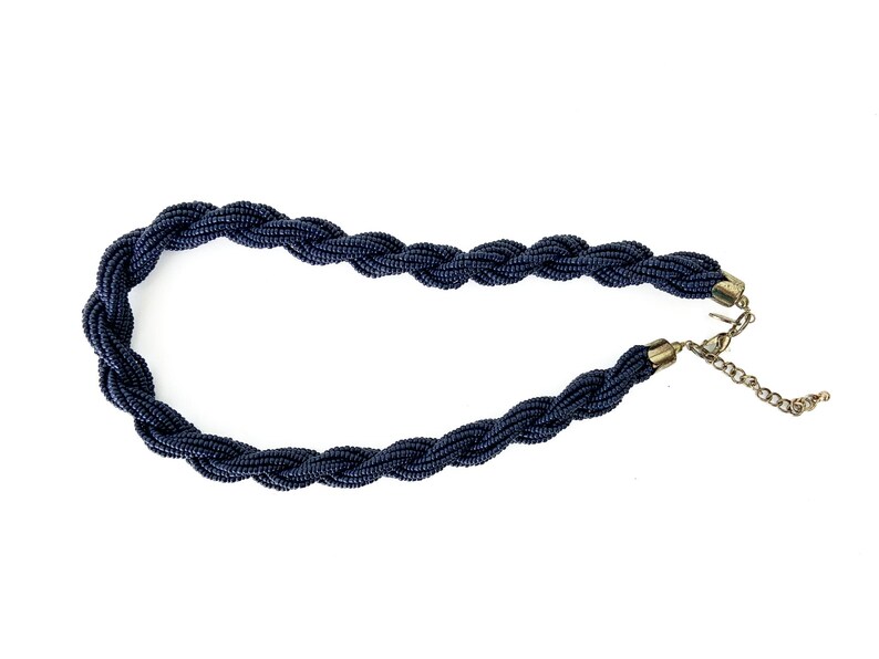 May include: A dark blue beaded necklace with a twisted design and a gold clasp.