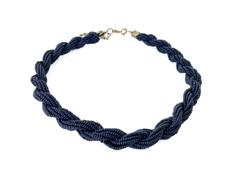 May include: A black beaded necklace with a twisted rope design.