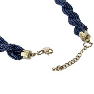 May include: A dark blue beaded necklace with a silver clasp and extender chain.
