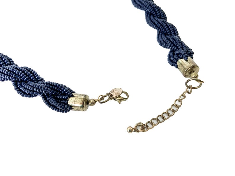 May include: A dark blue beaded necklace with a silver clasp and extender chain.