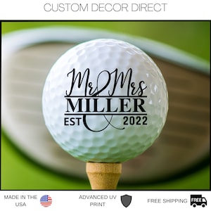 May include: White golf ball with black text that reads "Mr & Mrs MILLER EST 2022".