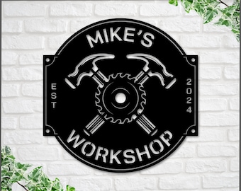 May include: Black metal sign with the text "Mike's Workshop" and the year "2024" in a circle. Two crossed hammers and a saw blade are in the center of the circle.