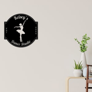 May include: Black and white sign with the text "Kelsey's Dance Studio" and a silhouette of a ballerina. The sign also includes the text "EST 2024".