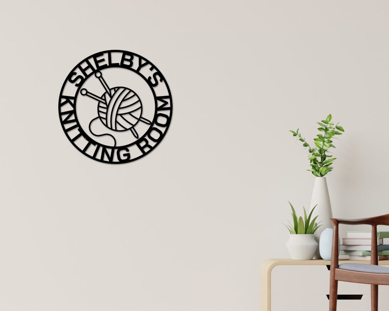 May include: Black metal sign with the text "Shelby's Knitting Room" in a circle with a yarn ball and knitting needles inside.