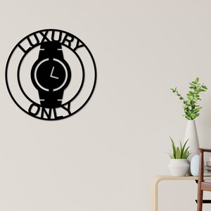 May include: Black metal wall decor with a circle design featuring a watch face and the words "Luxury Only".