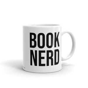 Op de afbeelding: Witte keramische mok met de tekst "BOOK NERD" in vette zwarte letters. De mok heeft een gebogen handvat en is geschikt voor warme dranken. Een eenvoudig en strak ontwerp.