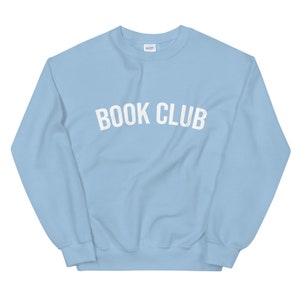May include: A light blue sweatshirt with the text "BOOK CLUB" in white.
