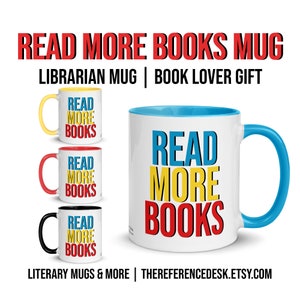 May include: White ceramic mug with a blue rim and handle. The mug has the text "READ MORE BOOKS" in colorful block letters. The text is in blue, yellow, and red. Three other mugs are shown in the background with different colored rims and handles.