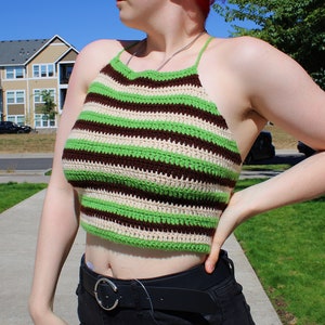 May include: A green, brown, and white striped crochet halter top. The top is cropped and has a relaxed fit.