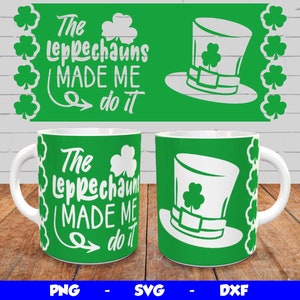 May include: Two white mugs with green backgrounds and white text that reads "The Leprechauns Made Me Do It". One mug has a green shamrock hat on it.