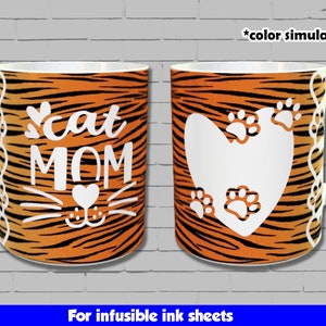 May include: Two white ceramic mugs with a tiger stripe pattern. One mug has the text "cat mom" with a cat face and a heart. The other mug has a white heart with paw prints. Both mugs are for infusible ink sheets.