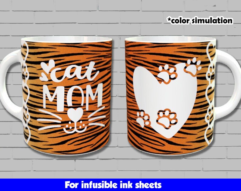 May include: Two white ceramic mugs with a tiger stripe pattern. One mug has the text "cat mom" with a cat face and a heart. The other mug has a white heart with paw prints. Both mugs are for infusible ink sheets.