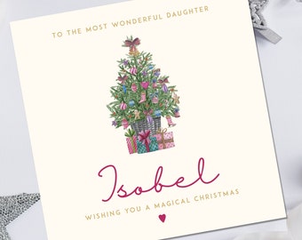 May include: A Christmas card with a watercolor illustration of a decorated Christmas tree with presents underneath. The card says "To the most wonderful daughter Isobel Wishing you a magical Christmas" with a pink heart.