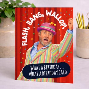 May include: Birthday card with a cartoon illustration of a man in a colorful striped suit and hat, with the words "FLASH, BANG, WALLOP!" and "WHAT A BIRTHDAY... WHAT A BIRTHDAY CARD" on a red background.