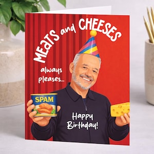 May include: A birthday card with a red background and the words "MEATS and CHEESES" in white. The card features an illustration of a smiling man wearing a party hat, holding a can of Spam and a block of cheese. The text "Happy Birthday!" is also on the card.
