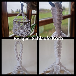 May include: White macrame hanging basket with a wooden ring. The basket is made with a knotting technique and has a loop at the top for hanging.