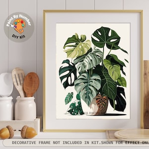 Peut inclure: Une impression encadr&eacute;e d'une plante Monstera avec de grandes feuilles vertes, dans un cadre dor&eacute;. L'image fait partie d'un kit de peinture par num&eacute;ros &agrave; faire soi-m&ecirc;me. Le texte en bas indique : "CADRE D&Eacute;CORATIF NON INCLUS DANS LE KIT. MONTRE &Agrave; TITRE D'EFFET UNIQUEMENT."