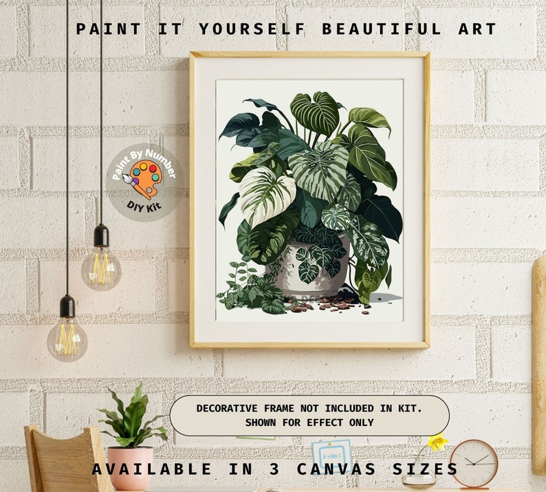 Op de afbeelding: Een ingelijste paint-by-number kit met een botanische illustratie van groene en witte planten in een decoratieve pot. Het kunstwerk wordt op een witte achtergrond weergegeven, met de tekst "PAINT IT YOURSELF BEAUTIFUL ART". Verkrijgbaar in 3 canvasmaten.