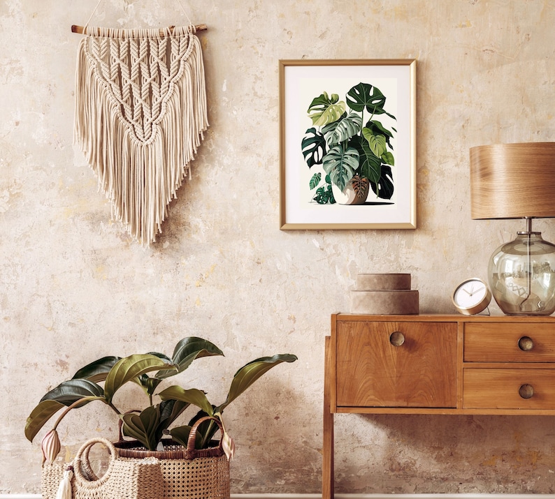 Peut inclure: Int&eacute;rieur de pi&egrave;ce avec une tenture murale en macram&eacute;, une impression botanique encadr&eacute;e et un meuble en bois avec une lampe et une horloge. Une plante en pot dans un panier tress&eacute; est au sol. La palette de couleurs comprend le beige, le marron et le vert.