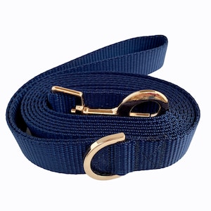May include: A navy blue dog leash with a gold metal clip and a gold metal ring. The leash is coiled up and ready to use.