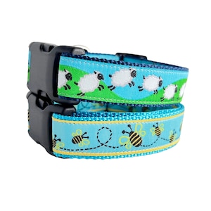 May include: A blue and green dog collar with a pattern of white sheep and yellow bees. The collar has a black buckle.