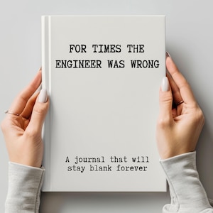 May include: A white journal held by hands, with the text "FOR TIMES THE ENGINEER WAS WRONG" and "A journal that will stay blank forever" printed in black. The journal is a hardcover book.