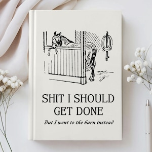 May include: Cream-colored notebook with a black and white illustration of a horse in a stable. The text on the cover reads "SHIT I SHOULD GET DONE" and "But I went to the barn instead."