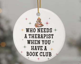 May include: White ceramic Christmas ornament with a book stack Christmas tree design and the text "Who needs a therapist when you have a book club".