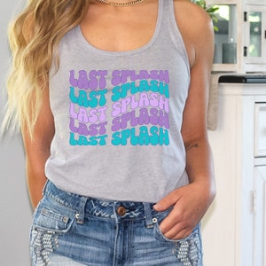 K&ouml;nnte beinhalten: Ein graues Tanktop mit dem Spruch "Last Splash", der f&uuml;nfmal in einer Retro-Schriftart in bunten Farben wiederholt wird. Der Text ist in Violett- und Blaut&ouml;nen gehalten.