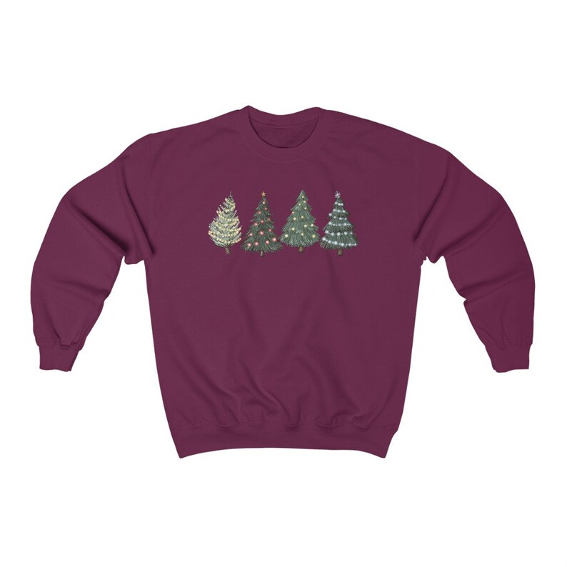 Peut inclure: Un sweat-shirt bordeaux avec une rang&eacute;e de quatre sapins de No&euml;l. Les arbres sont d&eacute;cor&eacute;s de divers ornements et lumi&egrave;res. Les arbres sont dans des tons de vert, blanc et or.