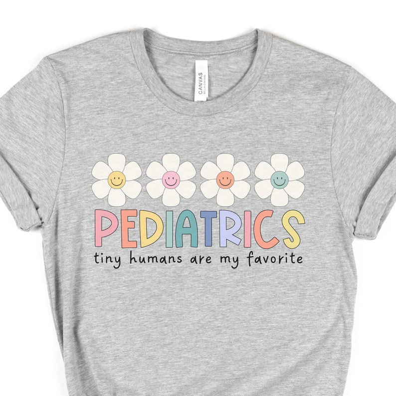 Pu&ograve; includere: Maglietta grigia con una grafica colorata di cinque margherite e il testo "PEDIATRICS tiny humans are my favorite".