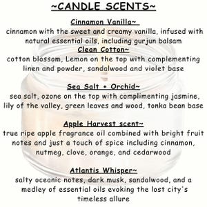 May include: A close-up of a candle jar with a white label listing different candle scents. The scents are: Cinnamon Vanilla, Clean Cotton, Sea Salt + Orchid, Apple Harvest, and Atlantis Whisper. Each scent description includes a list of fragrance notes.
