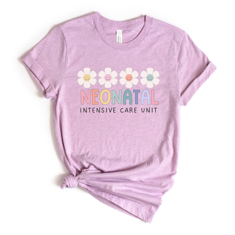May include: A light purple t-shirt with a graphic design of five colorful daisies and the text "NEONATAL INTENSIVE CARE UNIT".