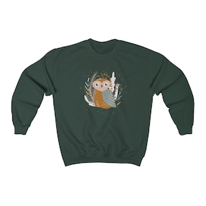 May include: A dark green sweatshirt with a cute cartoon owl in a forest setting. The owl is brown and gray with big eyes and is surrounded by leaves and branches.