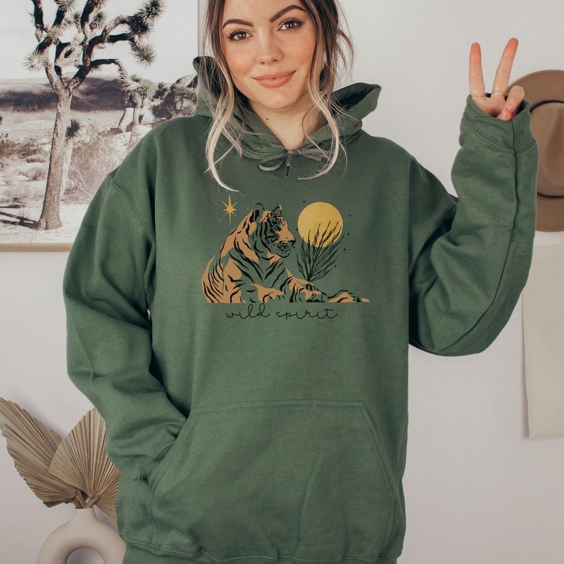 May include: A green hooded sweatshirt with a graphic print of a tiger sitting under a yellow moon with the text "wild spirit" below the tiger.
