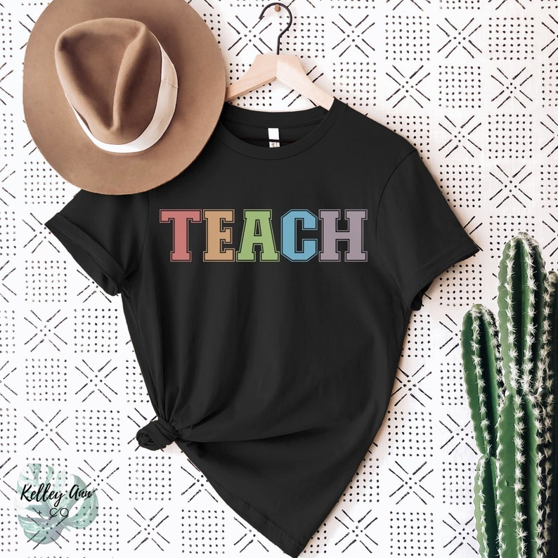 May include: Black t-shirt with the word "TEACH" in rainbow colors. The letters are outlined in white.