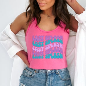K&ouml;nnte beinhalten: Ein pinkfarbenes Tanktop mit dem Text "LAST SPLASH", der f&uuml;nfmal in einer Retro-Wellenschrift wiederholt wird. Der Text ist in Schattierungen von Lila, Blau und T&uuml;rkis.