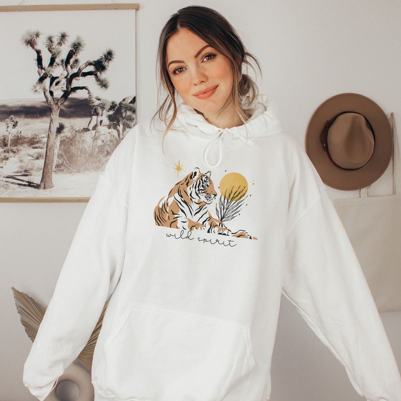 May include: White hooded sweatshirt with a graphic of a tiger, a sun, and a star. The text "wild spirit" is printed below the tiger.