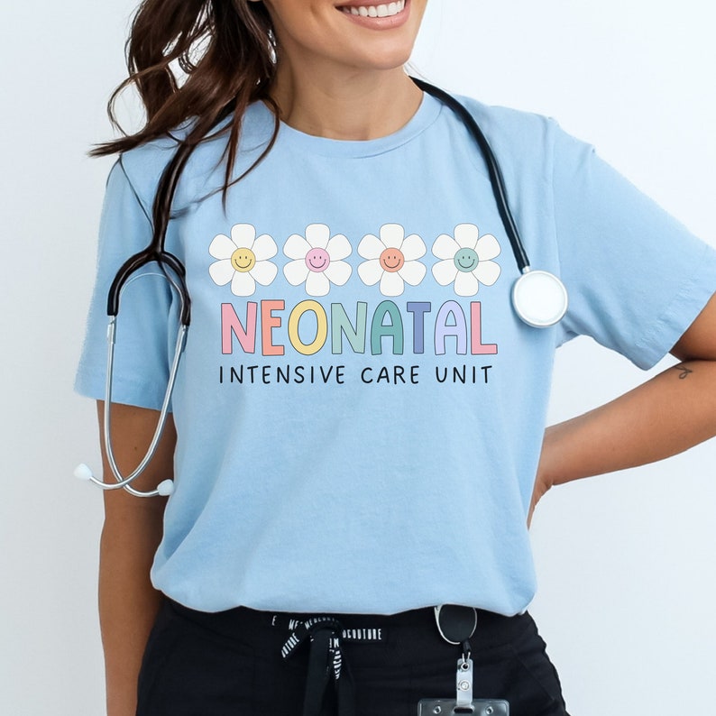 May include: Light blue t-shirt with a row of five colorful smiling daisy flowers and the text "NEONATAL INTENSIVE CARE UNIT".