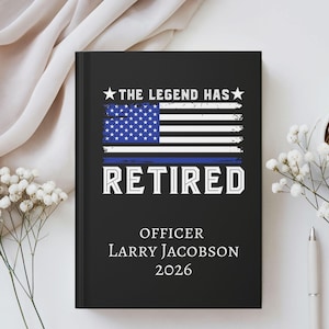 May include: Black journal with the text "THE LEGEND HAS RETIRED" above a distressed American flag design with a blue stripe. Below the flag are the words "OFFICER" and "Larry Jacobson 2026".