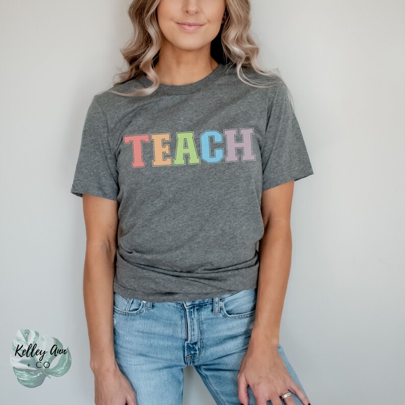 May include: A gray t-shirt with the word "TEACH" printed in rainbow colors.